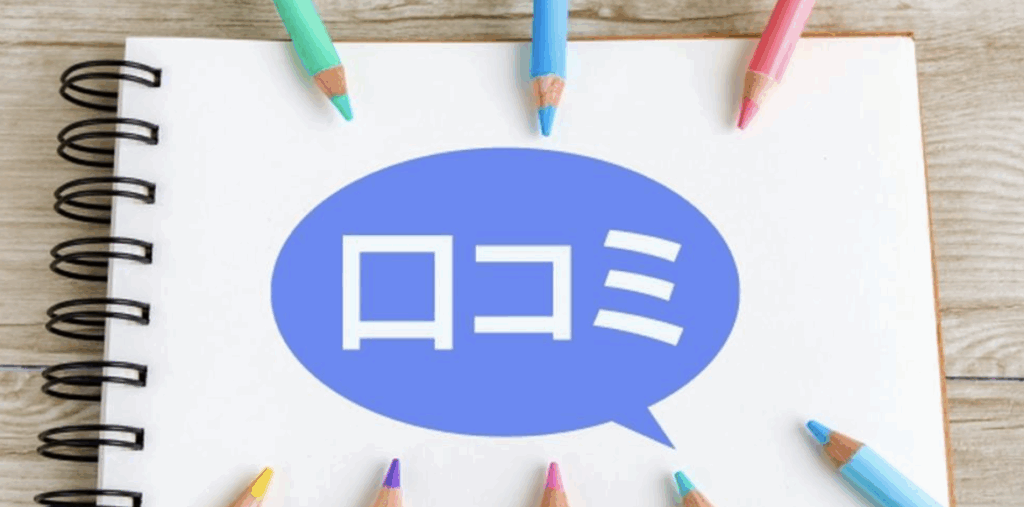 口コミをイメージした写真—ノート中央の吹き出しに「口コミ」の文字、周囲に並ぶカラフルな色鉛筆